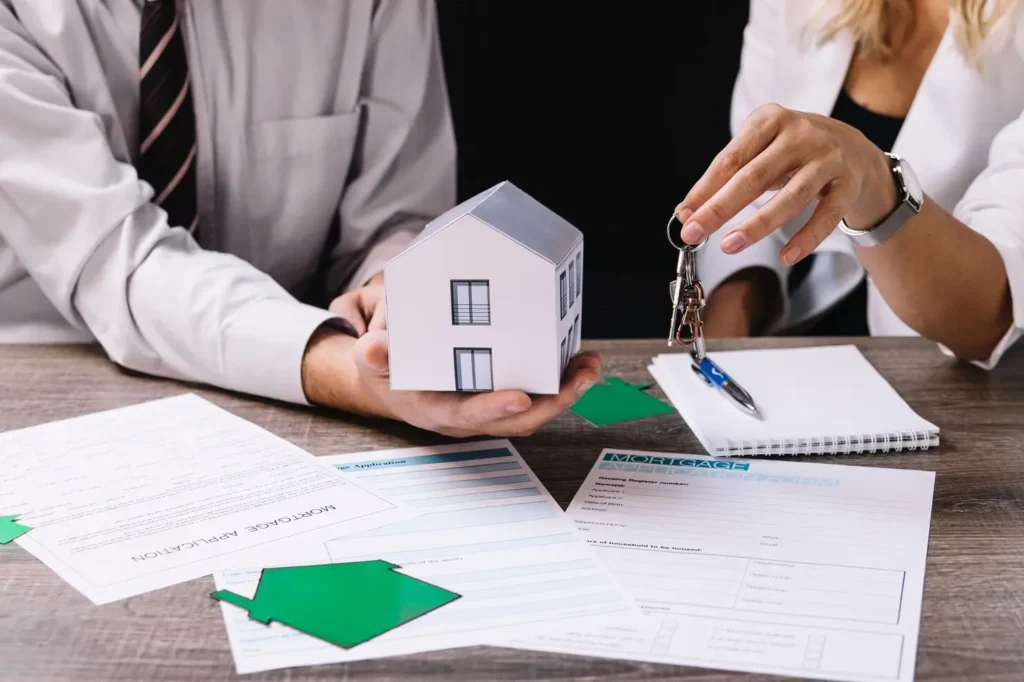 Man holding a model house and keys, discussing property division during a divorce, with legal documents on the table, symbolizing family law services in Humble, Texas.